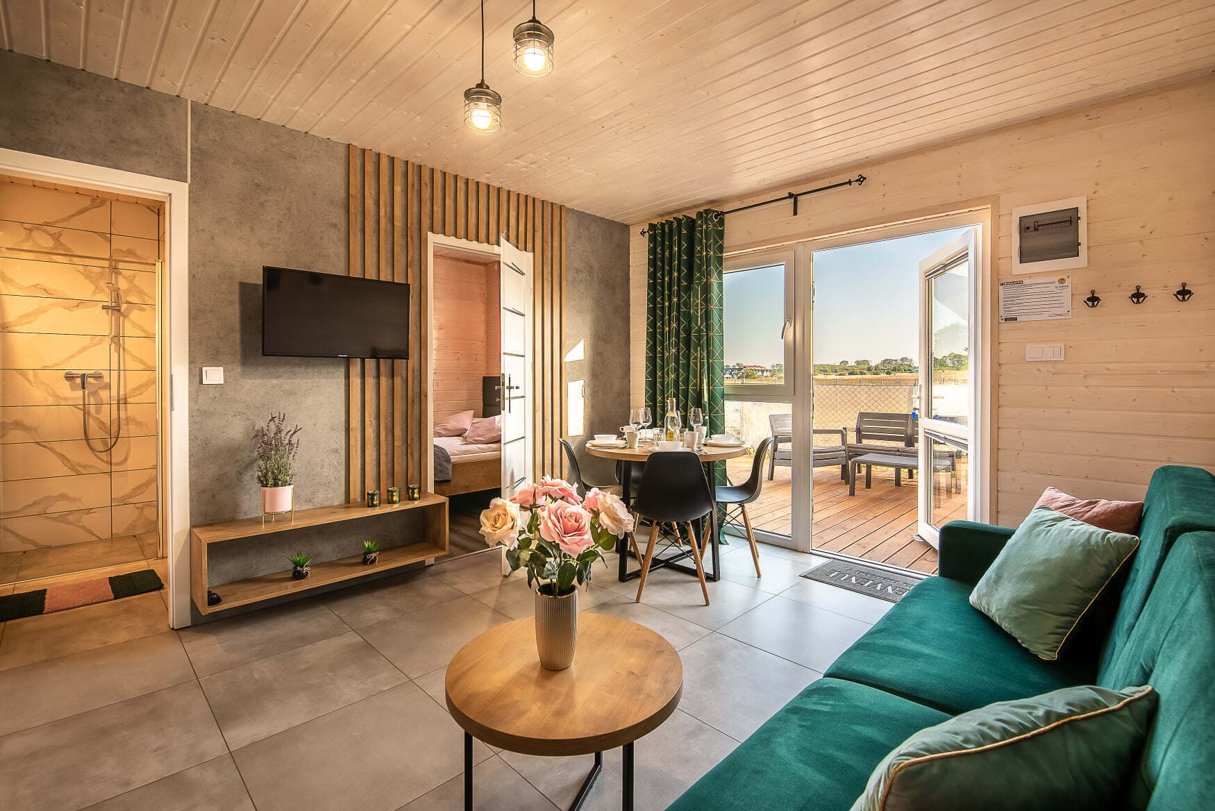 Salon apartamentu w Sarbinowie z zieloną sofą i wyjściem na taras