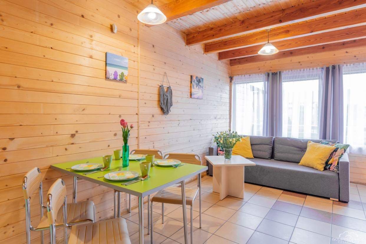 Living room of a two-storey cottage in Sarbinowo — wooden walls, laid table and sofa