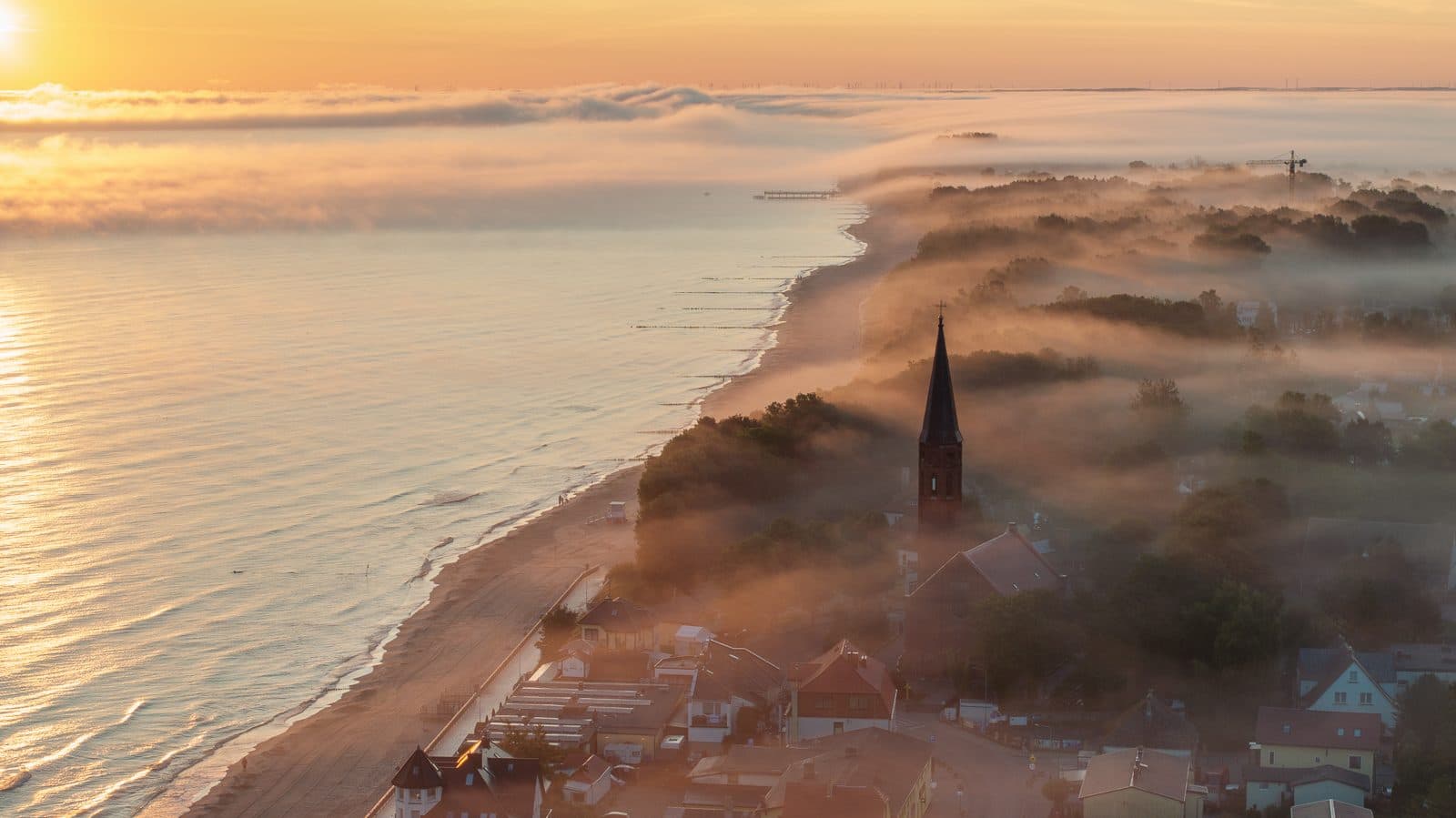 Morning mist over Sarbinowo and the church tower at dawn