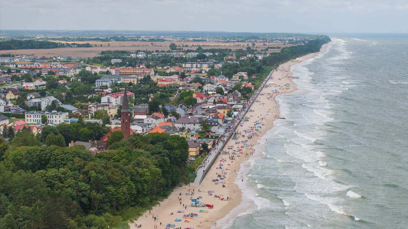 Panorama Sarbinowa z lotu ptaka: zabudowa, las i plaża nad Bałtykiem